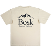 The Bosk Outdoors Tee by BOSK features a beige color with a centered mountain silhouette and the word "Bosk" in bold black text on the back. Below, smaller text reads "Bay Area Outfitters," creating a clean, outdoor-inspired aesthetic.